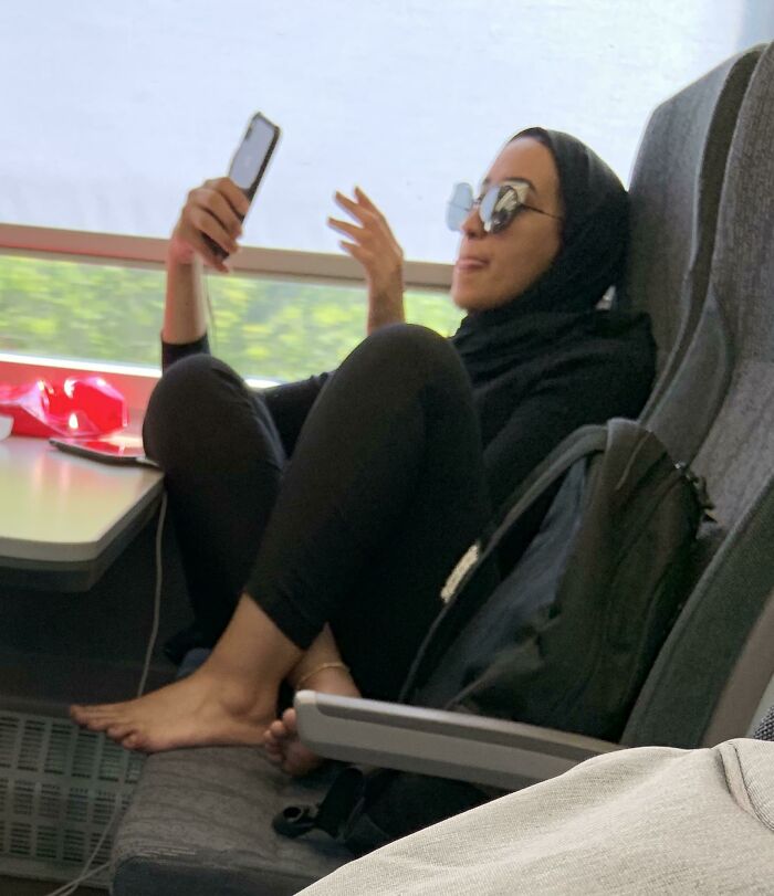 Passenger with feet on seat, holding phone on public transport.