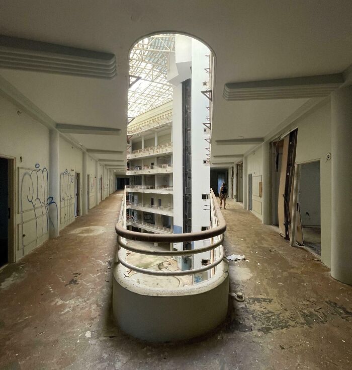 Abandoned building atrium with curved railing, peeling walls, and skylight; an interesting, not photoshopped photo.