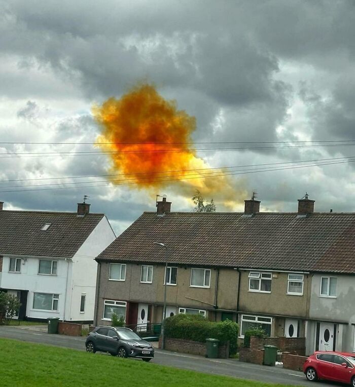 A bright orange cloud hovering above suburban houses, showcasing an interesting, not photoshopped photo phenomenon.
