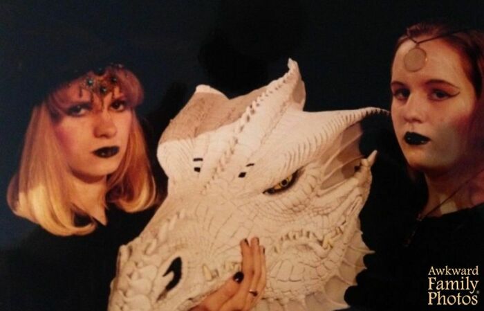 Two people pose with a large white dragon head, embodying an awkward family photo theme.