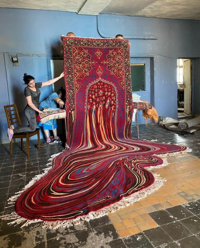 People holding a unique carpet that appears to melt into the floor—an interesting, not photoshopped visual effect.