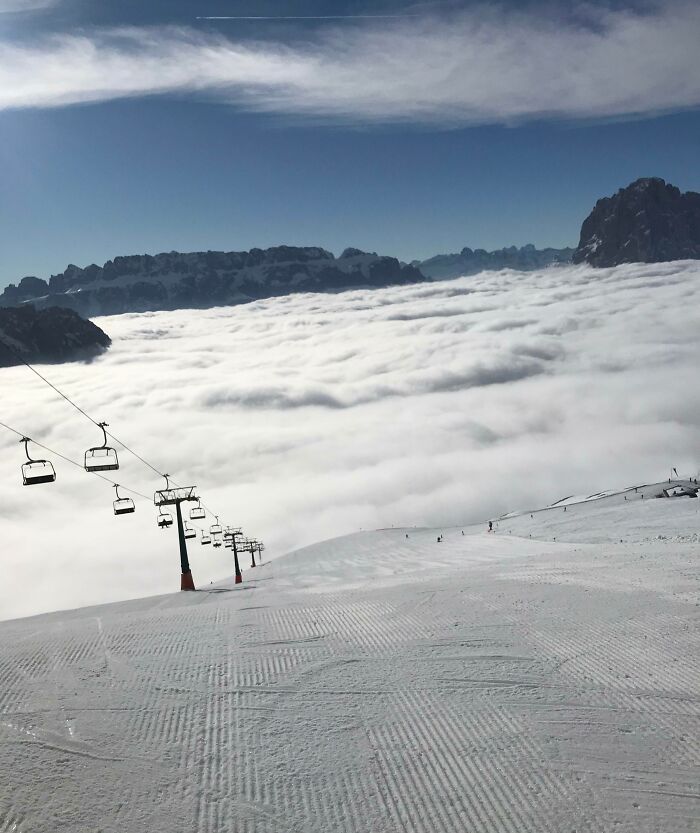 Ski lift over a snowy mountain with a sea of clouds, showcasing an interesting, not photoshopped photo of scenic beauty.