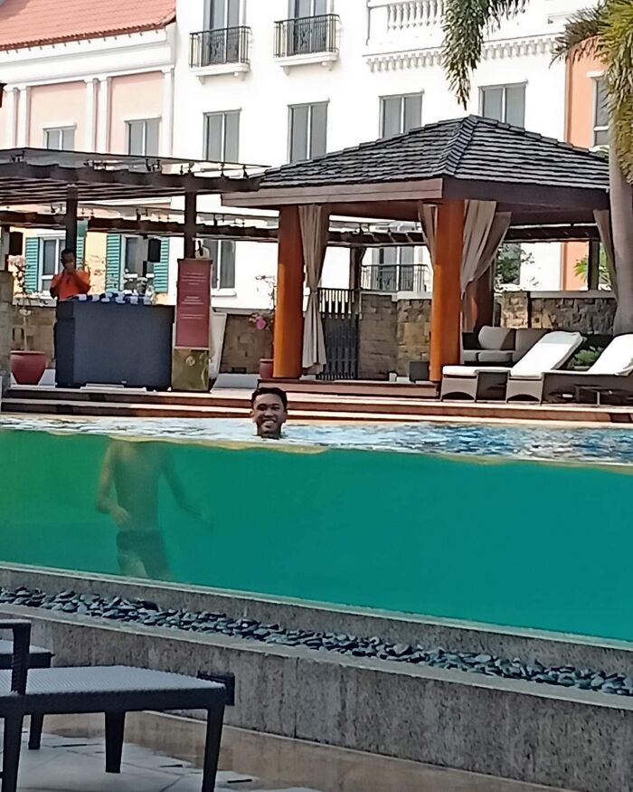 Man appearing to float above water in a transparent pool, showcasing interesting not photoshopped photo illusion.