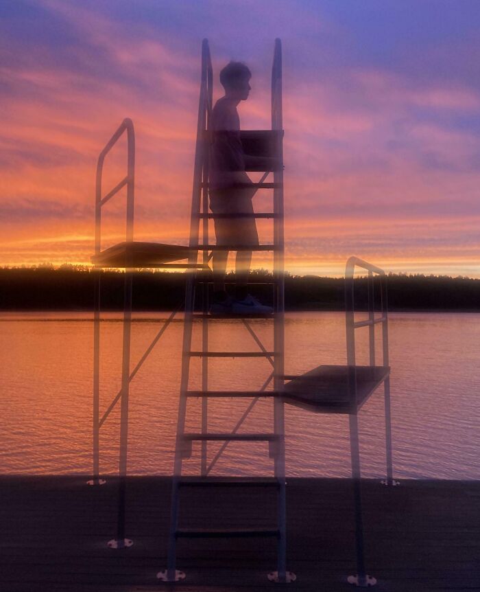 Silhouette of a person standing on a ladder by the lake at sunset, creating an interesting visual illusion, not photoshopped.