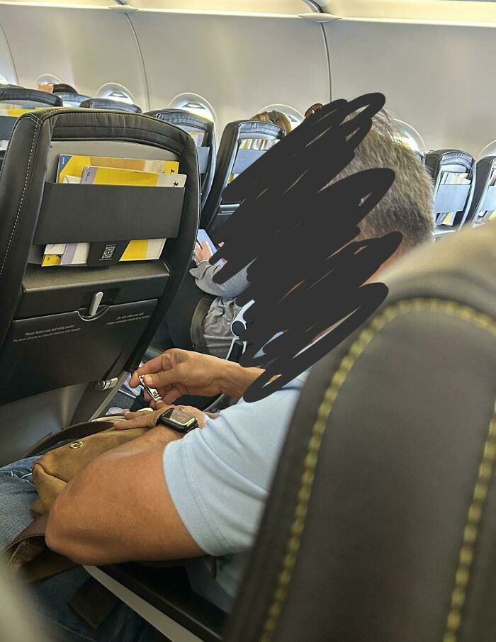 Airplane passenger with an armrest dispute, adjusting belongings during flight.