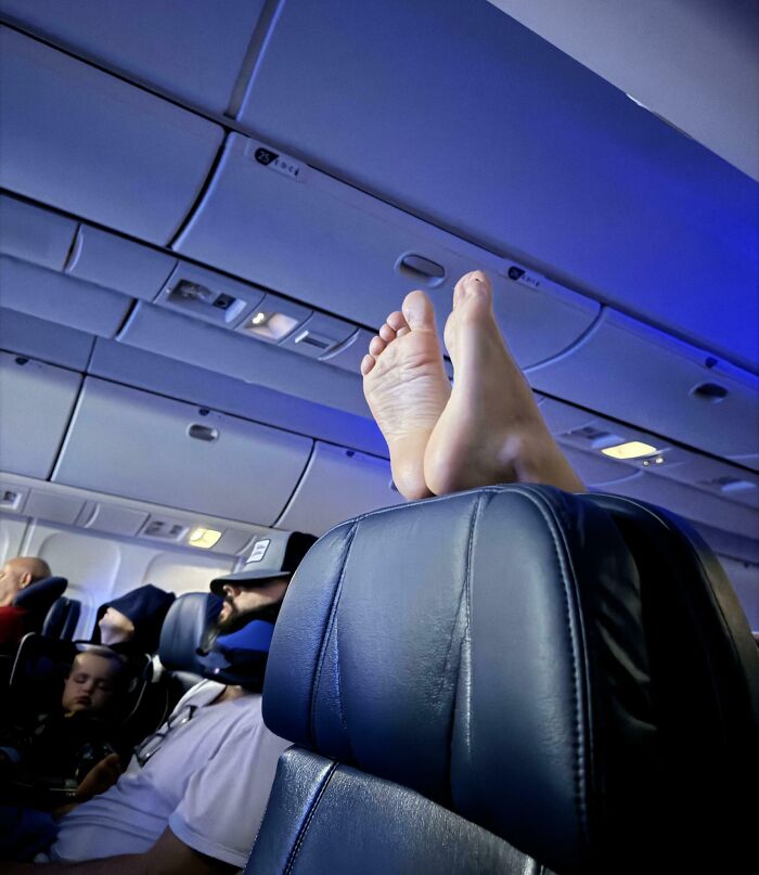 Bare feet resting on airplane seat, exemplifying annoying plane passengers.