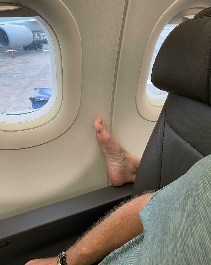 Bare foot on a plane wall, illustrating annoying plane passengers.