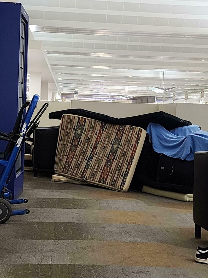 Makeshift fort of airplane seats and blue blanket, possibly by annoying plane passengers, in an airport.