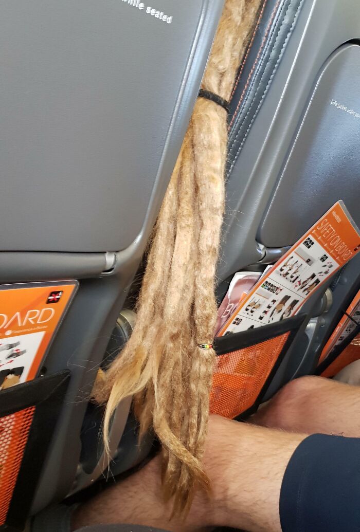 Dreadlocks drape over airplane seat, highlighting annoying-plane-passengers' habits.