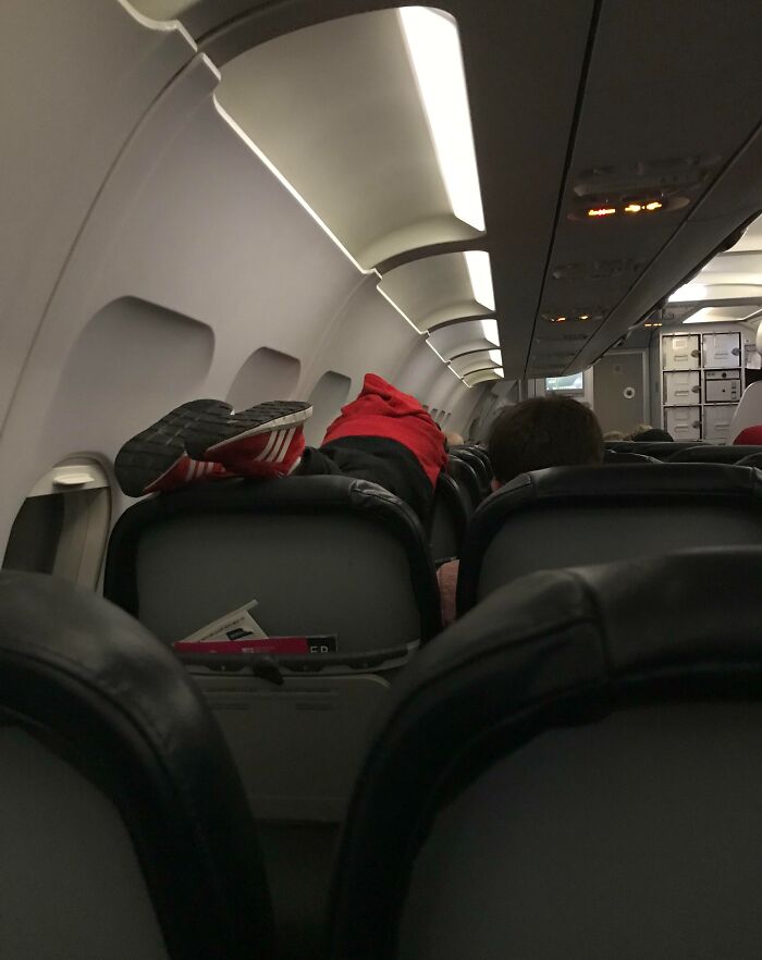 Passenger lying across multiple seats in an airplane cabin, exemplifying annoying plane passengers.