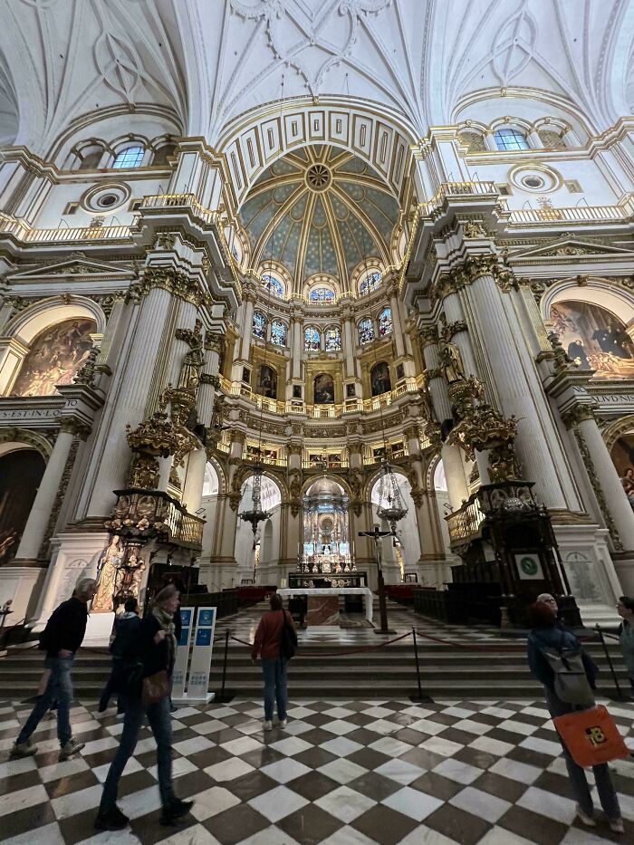 Interior view of an impressive architectural feat featuring ornate columns, stained glass, and a domed ceiling with visitors walking inside.