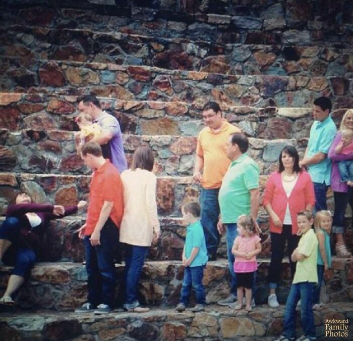 Awkward family photo with people in colorful clothes on stone steps, capturing a candid and humorous moment.