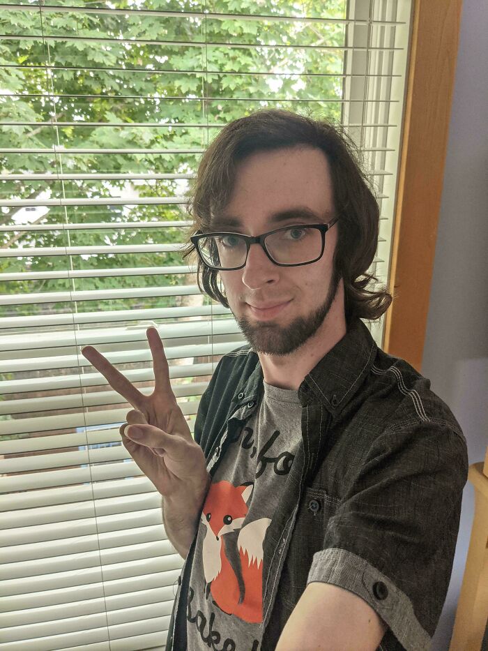 Young person in glasses and a fox shirt, making a peace sign, capturing a playful moment during their blunder years.