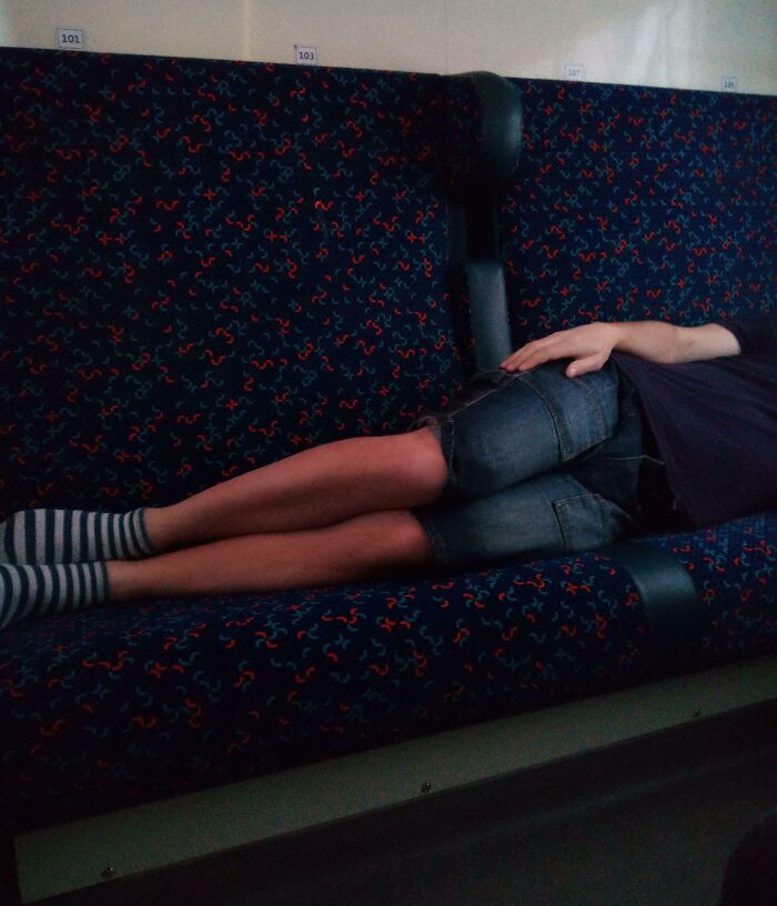 A public transport passenger taking up multiple seats by lying down in casual attire.