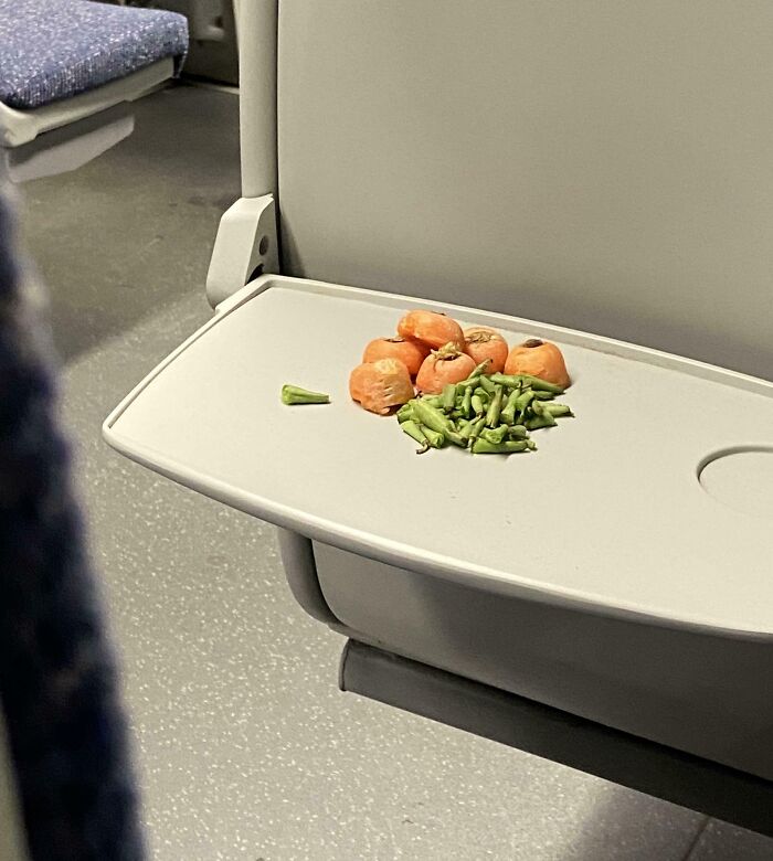 Chopped carrots and green beans left on a public transport seat tray.