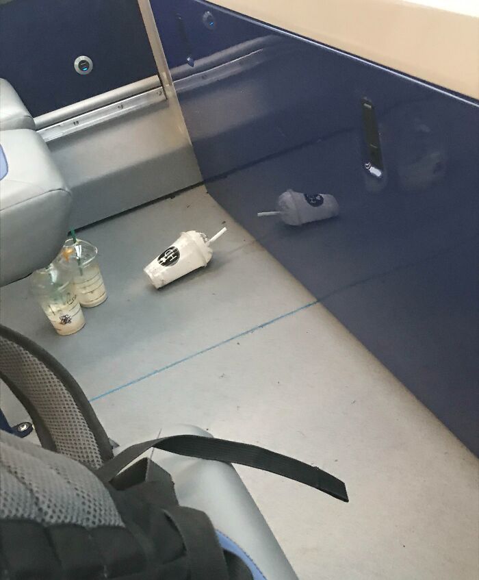 Abandoned drinks litter the public transport floor, showcasing infuriating passenger behavior.