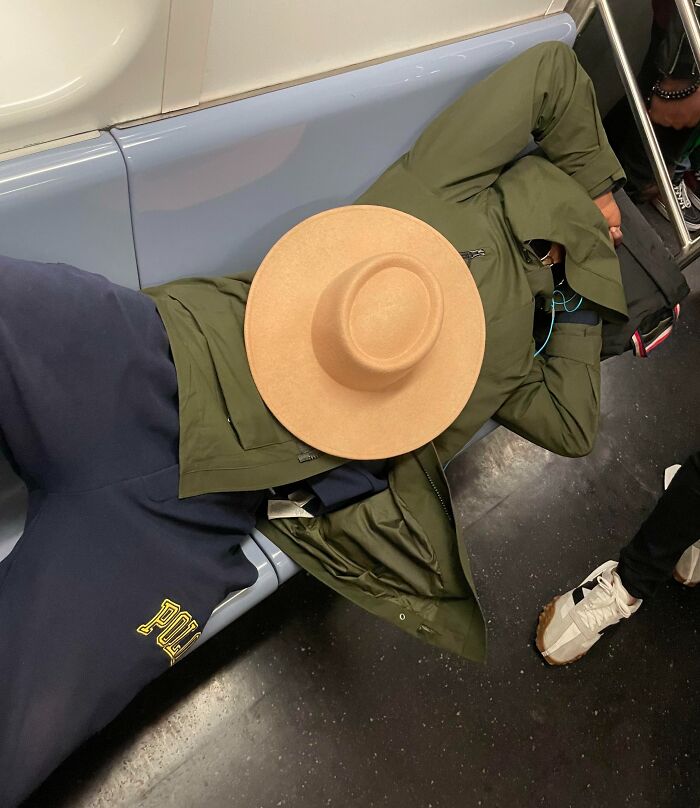 Passenger sprawled across subway seats, taking up space, wearing a large hat, illustrating public transport passenger issues.