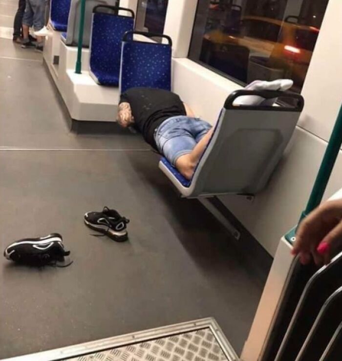 Person lying across bus seats, shoes on the floor, illustrating infuriating public transport behavior.