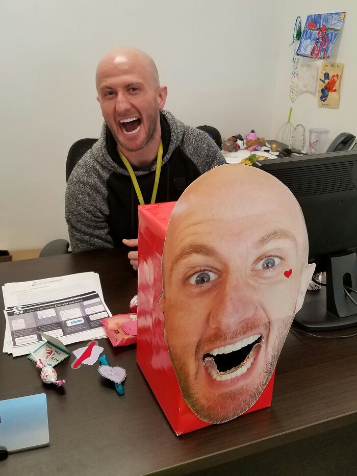Funny boss at desk with a large, humorous face cutout and playful desk decorations.