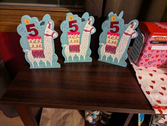 Llama-themed birthday cards featuring the number 5 on a wooden shelf, related to hilarious in-laws.