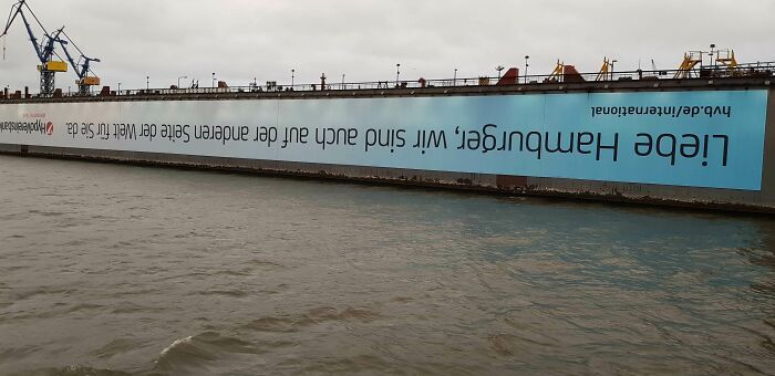 Upside-down billboard on a dock, illustrating a funny ad fail over water in Hamburg.
