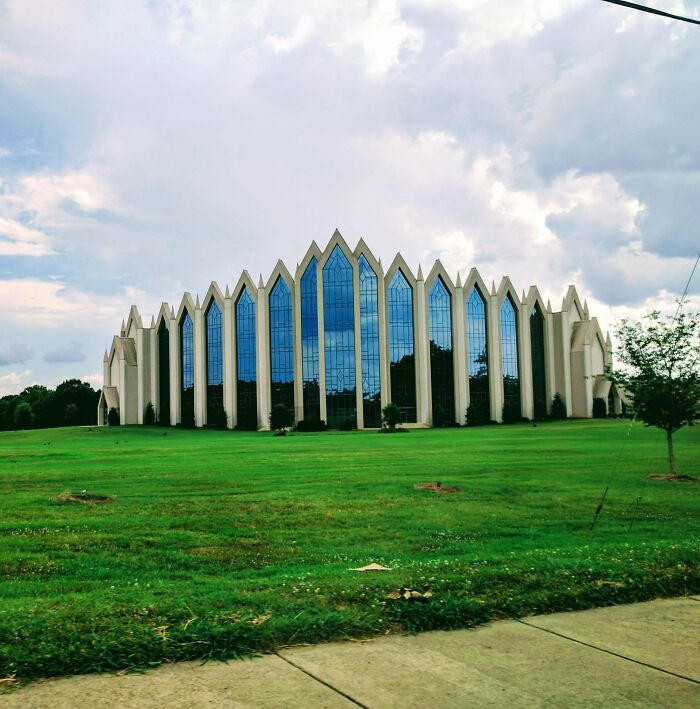 Modern building with sharp, angular windows and reflective glass, exuding an evil aura like a supervillain headquarters.