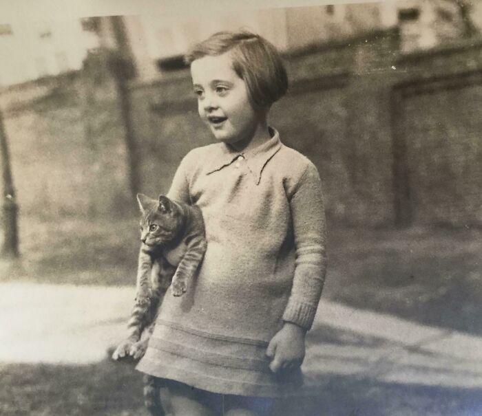 Child holding cat, vintage photo showing pets as family.