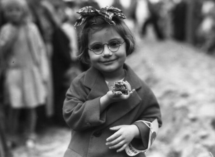 Child in vintage attire holding a small pet in black and white photo, showcasing a family bond.