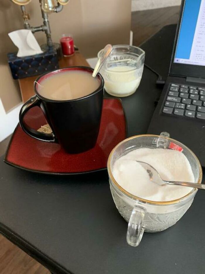 Cup of coffee and sugar next to a laptop, a cozy setup reflecting amazing mothers-in-law's hospitality.