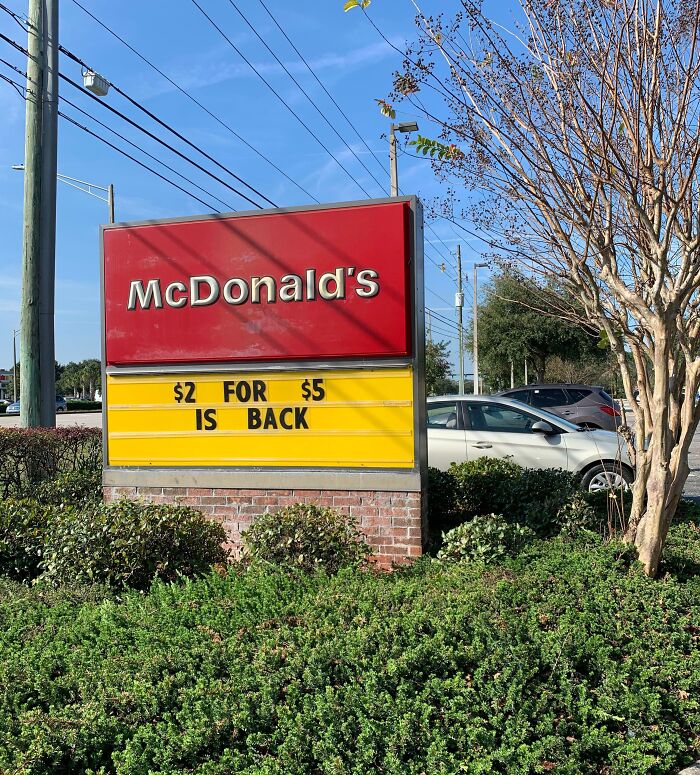 McDonald's sign displaying humorous fail, reading "$2 for $5 is back," under a sunny blue sky.