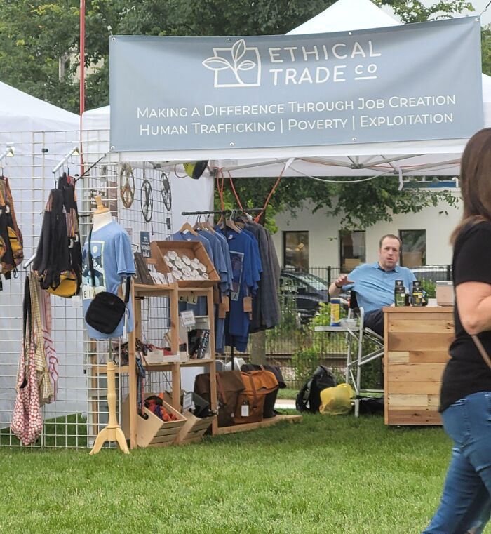Outdoor market booth with a confusing sign about ethical trade and human trafficking, depicting a funny ad fail.