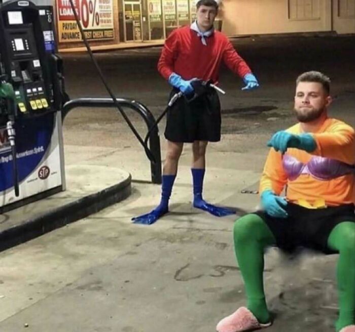 Two men in quirky costumes at a gas station, revving invisible vehicles. Humorous scene showcasing pics that go hard.