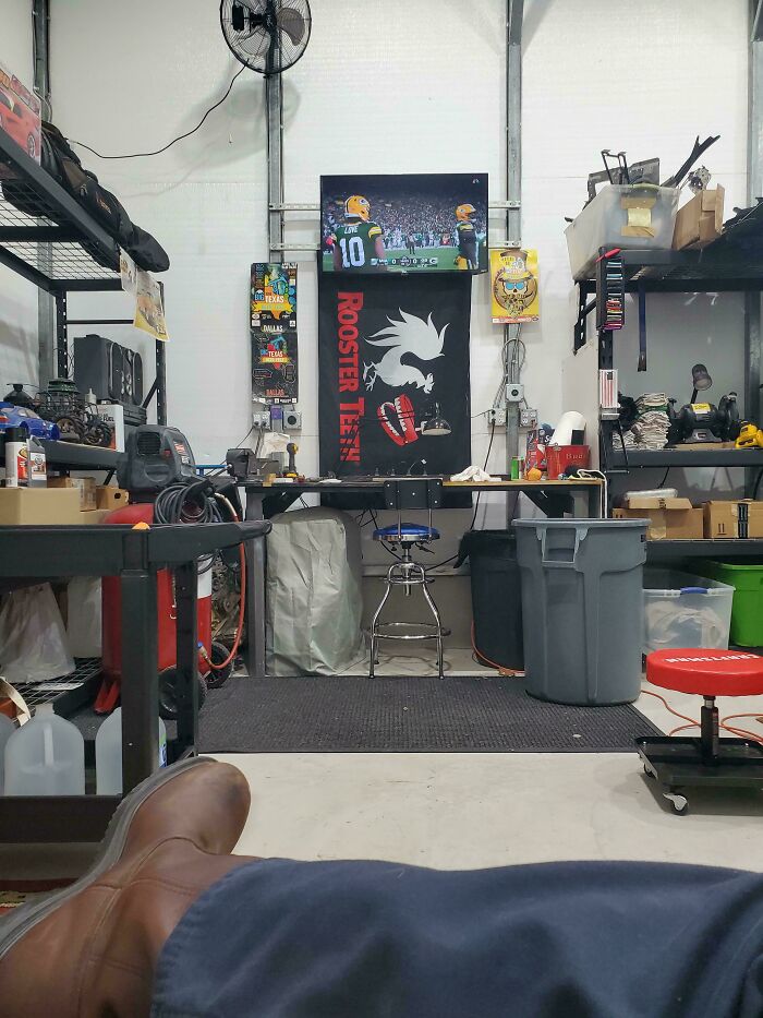 View of a dad's organized workshop with tools, storage bins, and a sports game on TV, showcasing wholesome dad moments.