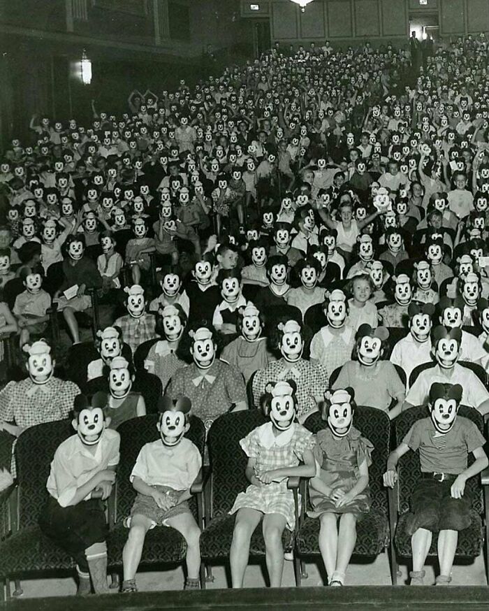Children wearing Mickey Mouse masks in a crowded theater, representing rarely seen historical photos.
