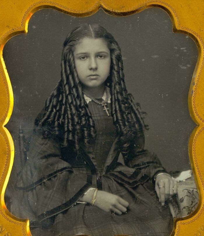 Vintage portrait of a young girl with long curls in a 19th-century dress, representing unseen historical photographs.