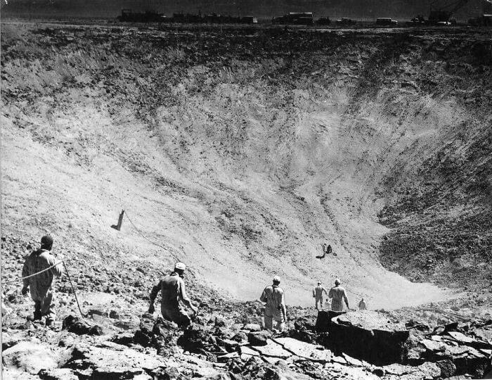 Soldiers inspecting a large crater, an unusual historical scene not commonly found in textbooks.