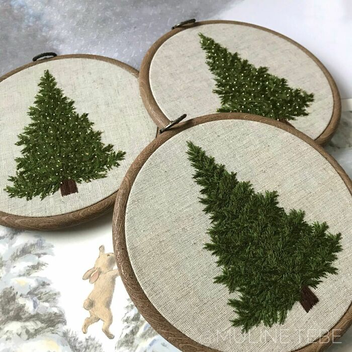 Embroidered Christmas trees as creative DIY decorations displayed in wooden hoops.