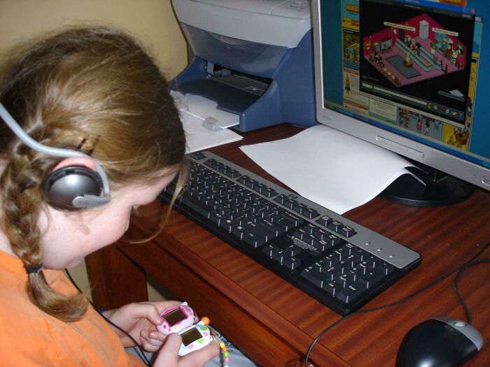 Girl with headset and virtual pet gadget at a computer, representing a blunder year moment.