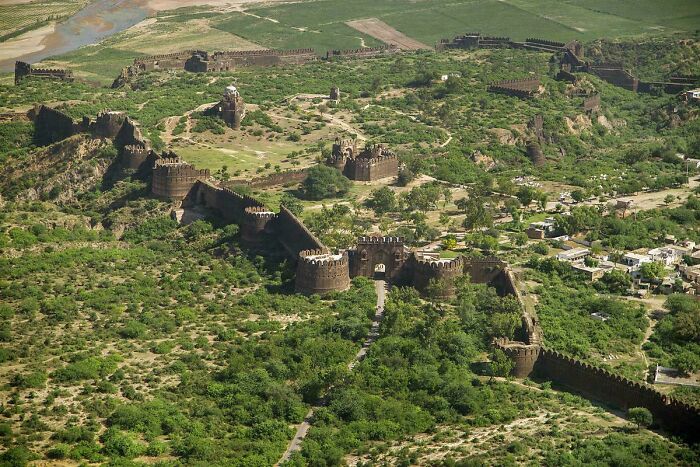 Aerial view of an impressive historic fortress showcasing remarkable architectural feats surrounded by greenery and villages.
