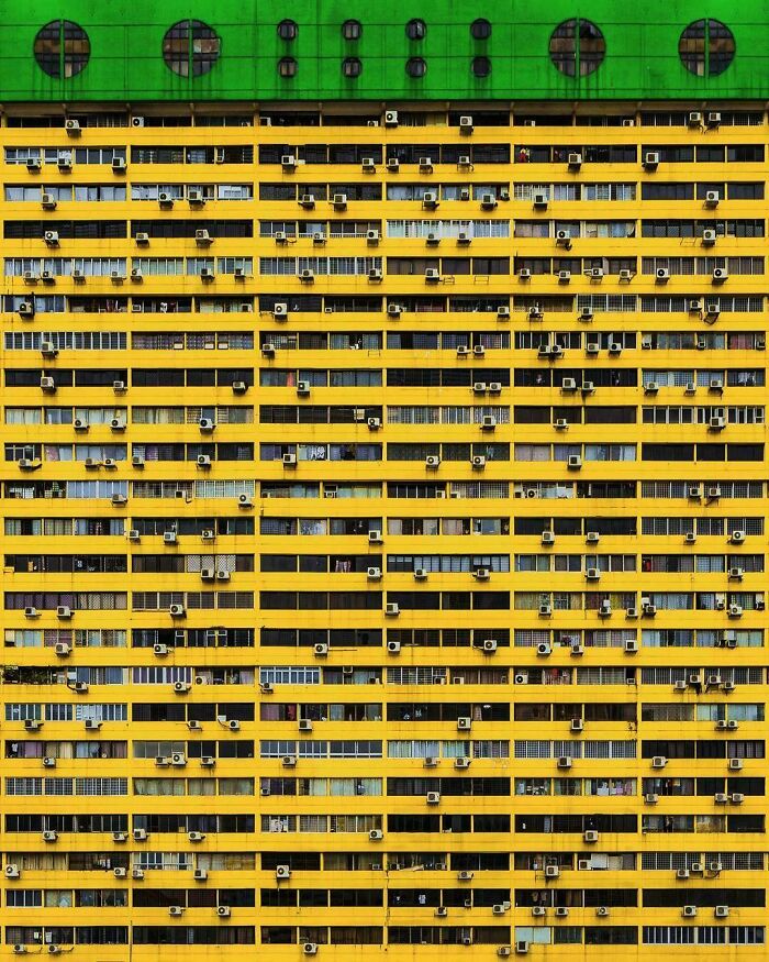 Yellow urban building with numerous air conditioning units, depicting urban hell architecture.