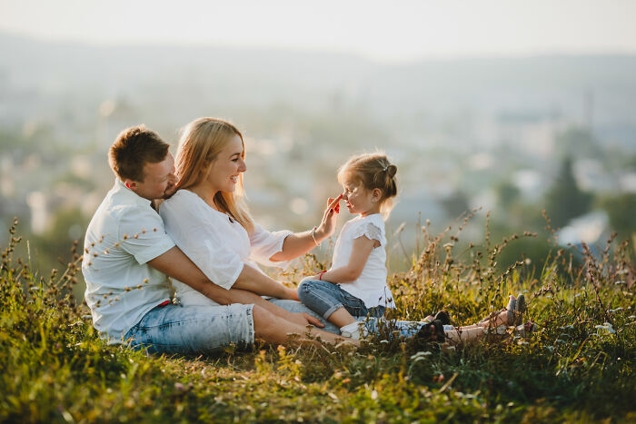 Family enjoying a sunny day on a grassy hill, symbolizing a risky decision to embrace outdoor relaxation.
