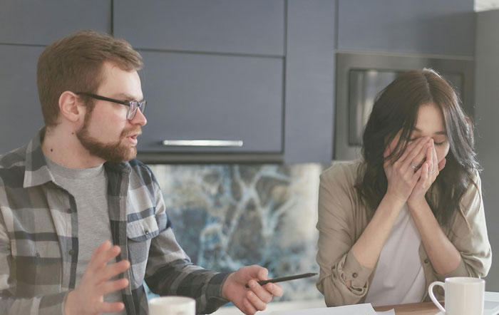 Father and woman in tense conversation at a kitchen table, highlighting family drama.