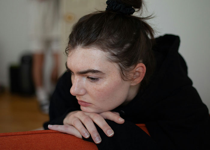 A woman in a thoughtful pose, wearing a black hoodie, illustrating the impact of savage insults.