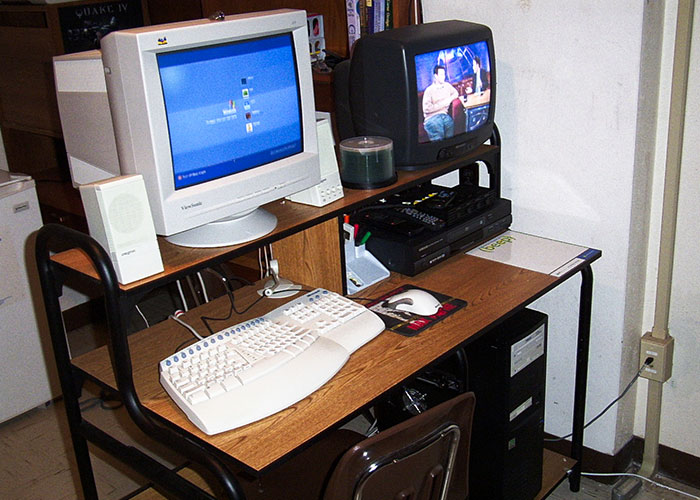 ‘90s and ‘00s trends: Retro computer setup with CRT monitor, keyboard, and classic TV with game console in a nostalgic room.