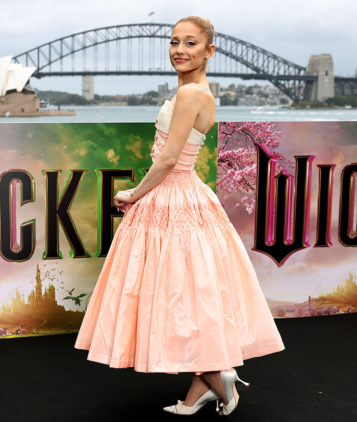 Robotic Thing: Woman in elegant peach dress at movie premiere, standing in front of scenic backdrop and bridge.