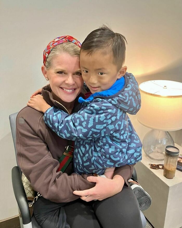 Woman hugging a young child, both smiling warmly, representing a wholesome adoption moment.