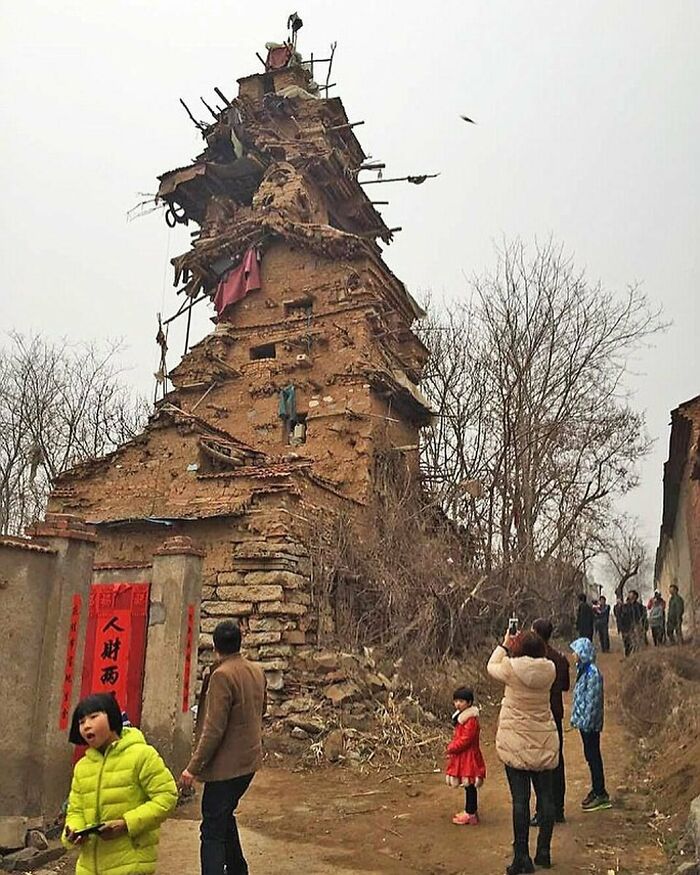 Ancient leaning tower made of bricks and mud with visitors taking photos, showcasing random facts and curiosities.