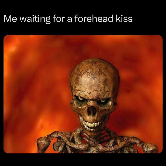 Skeleton with a creepy smile on a fiery background, captioned "Me waiting for a forehead kiss." Funny memes with horror.