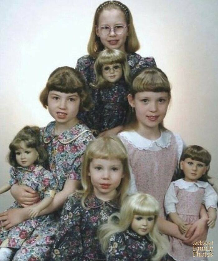Awkward family photo of four children with matching dolls in floral dresses, capturing a humorous and memorable moment.