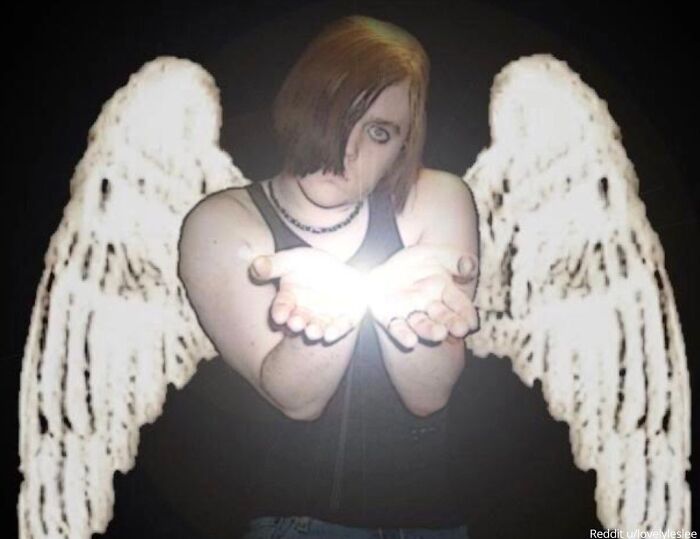 Person with angel wings posing dramatically, holding a glowing light in hands; viral family photo moment.